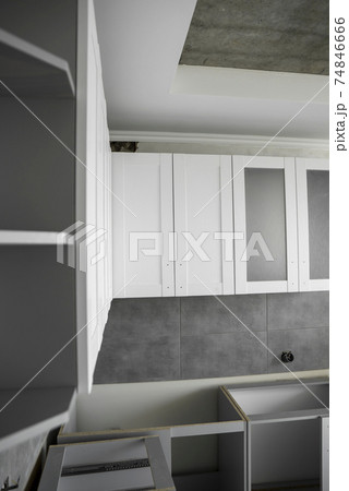 Custom kitchen cabinets installation with a furniture facades mdf. Gray modular kitchen from chipboard material on a various stages of installation. A frame furniture fronts mdf profile. 74846666