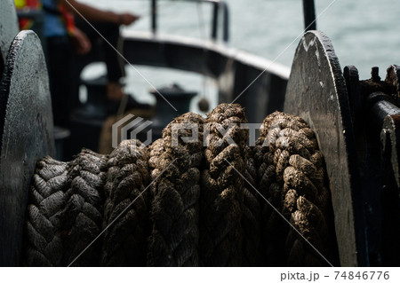 Rope on a sea boat for mooring a vessel is adhered to a pier. 74846776