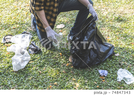 Male volunteers carry water bottles or plastic bags that have fallen in the park put them in trash cans, Environmental protection or volunteering for charity, Waste disposal through recycling. Male volunteers carry water bottles or plastic bags that have fallen in the park put them in trash cans, Environmental protection or volunteering for charity, Waste disposal through recycling. 74847343