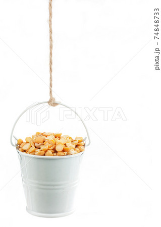 A full bucket of peas grains hanging from a rope. A full bucket of peas grains hanging from a rope. 74848733