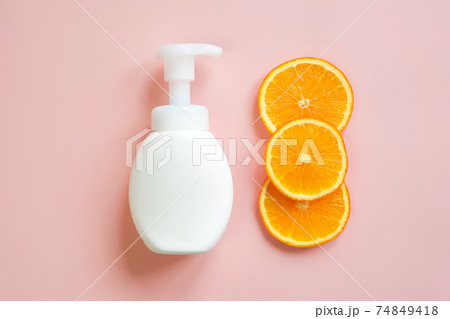 White pump cream bottle and orange slices border on pink background. Liquid soap or cleansing cream bottle. Cosmetic packaging mockup with copy space, template, front view White pump cream bottle and orange slices border on pink background. Liquid soap or cleansing cream bottle. Cosmetic packaging mockup with copy space, template, front view 74849418