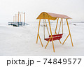An old swing against the background of a snowy shore. 74849577