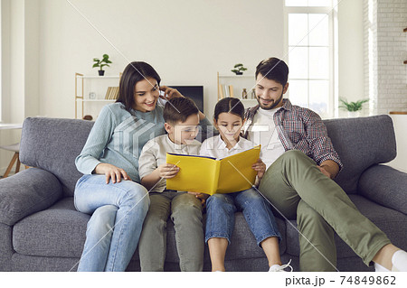 Happy family with children enjoying free time at home and reading a book together Happy family with children enjoying free time at home and reading a book together 74849862