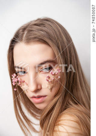 Gentle young woman in lingerie with flowers on face Gentle young woman in lingerie with flowers on face 74850087