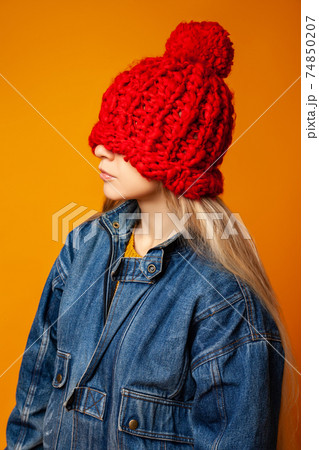Hipster woman in red knitted hat against orange background 74850207