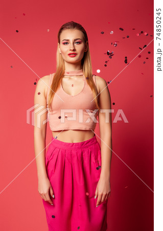 Stylish woman in pink apparel with confetti Stylish woman in pink apparel with confetti 74850245