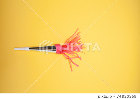 Party horn and scattered shiny confetti on orange background Party horn and scattered shiny confetti on orange background 74850569