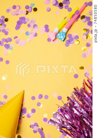 Assorted party supplies with glowing confetti scattered on table Assorted party supplies with glowing confetti scattered on table 74850580