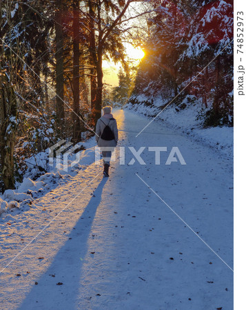 Woman hiking on snow in white winter forest berore the sunset. Recreation and healthy lifestyle outdoors in nature 74852973