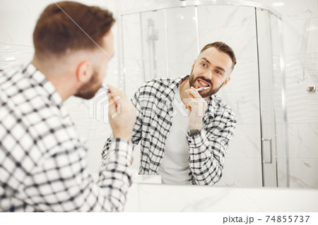 Portrait view of a young man brushing his teeth Portrait view of a young man brushing his teeth 74855737
