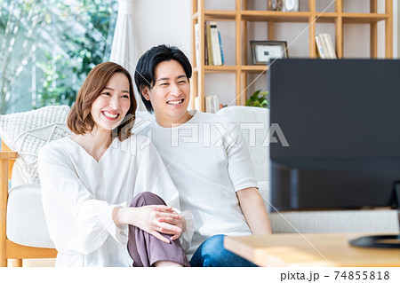リビングでテレビを見る若い夫婦 リビングでテレビを見る若い夫婦 74855818