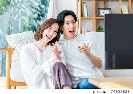 リビングでテレビを見る若い夫婦 74855823