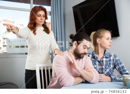 Portrait of sad mature woman trying to talk with adult children in home 74856132