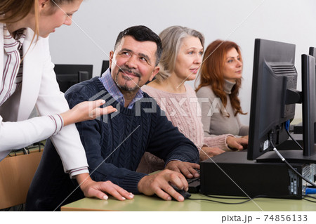 Businesswoman helping to coworkers, pointing at computer monitor 74856133