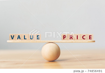 Wooden seesaw scale empty on wooden sphere on wood table with wording VALUE and PRICE balancing 74856491