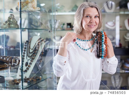 Woman trying on a turquoise necklace and earrings at a jewelry store 74856503