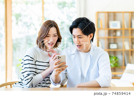 スマホを見る若い夫婦 スマホを見る若い夫婦 74859414