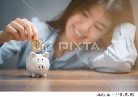 Bitcoin, Woman is putting golden bitcoin into the piggy bank. Bitcoin, Woman is putting golden bitcoin into the piggy bank. 74859690