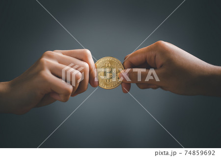 Two hands holding and pulling golden bitcoin. 74859692