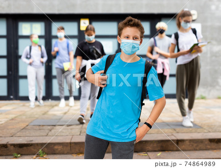 Young student in a protective mask going to college down city street 74864989