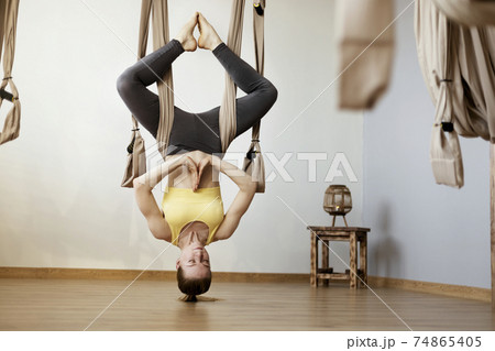 Sports girl is engaged in Aero yoga and performs asanas with the help of the hammock. Yoga, fitness, sports 74865405