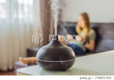 Aromatherapy Concept. Wooden Electric Ultrasonic Essential Oil Aroma Diffuser and Humidifier. Ultrasonic aroma diffuser for home. Woman resting at home 74865700