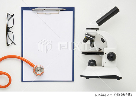 Doctor table with microscope, stethoscope and glasses, top view 74866495