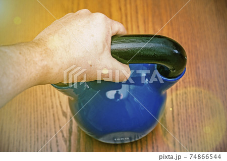 Iron kettlebell in the man's hand on a wooden background. kettlebells on gym. Close up. Sports kettlebell in the gym, top view. toned 74866544
