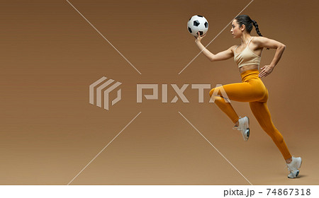 Website header of Athletic young woman with soccer ball running in studio 74867318