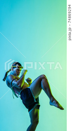 Portrait of young man thai boxer training over blue background. 74869294
