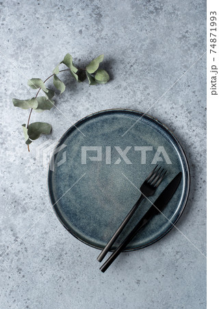 An empty plate and cutlery on a gray table. 74871993