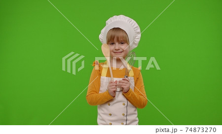 Girl kid dressed as cook chef baker posing, smiling, looking at camera on chroma key background 74873270