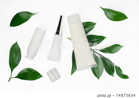 Flat lay view at white cosmetic bottles and containers with green leaves on white table 74875634