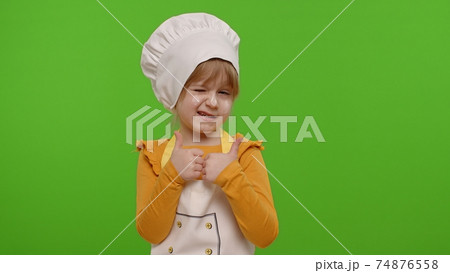 Child girl kid dressed as cook chef showing thumbs up, smiling, looking at camera on chroma key 74876558