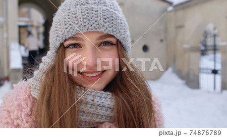 Portrait of Caucasian pretty happy girl with smile on face posing on winter citystreet background 74876789