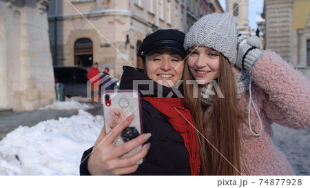 Sisters couple bloggers taking selfie, making video conferencing call on mobile phone on city street 74877928