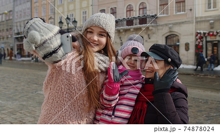 Sisters tourists taking selfie, posing, making video conferencing on mobile phone on city street 74878024