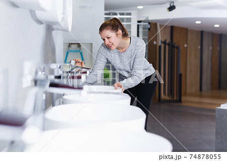 Smiling woman buyer looking ceramic washbasin with tap Smiling woman buyer looking ceramic washbasin with tap 74878055