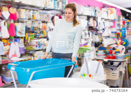 attentive pregnant female is buying bath for baby in the store attentive pregnant female is buying bath for baby in the store 74878164