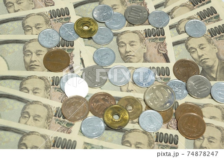 たくさん広がっている一万円の上に散らばる小銭・硬貨 74878247