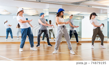 Happy smiling teenagers practicing vigorous hip hop movements in class 74879195