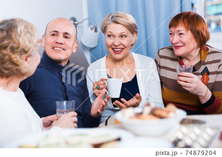 Mature women and their friend are drinking tea and talking Mature women and their friend are drinking tea and talking 74879204