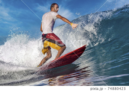 Male surfer on a blue wave 74880423