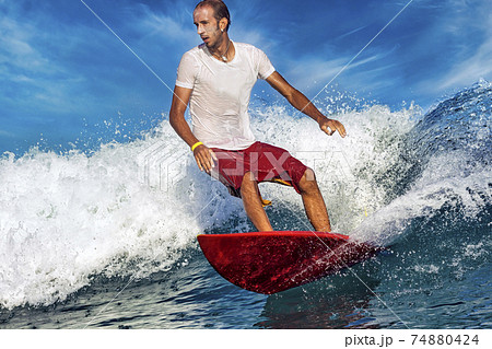 Male surfer on a blue wave 74880424
