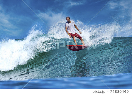 Male surfer on a blue wave Male surfer on a blue wave 74880449