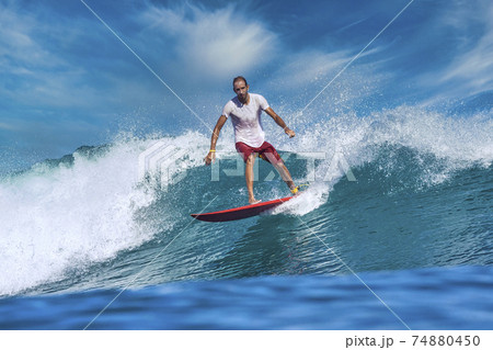 Male surfer on a blue wave Male surfer on a blue wave 74880450