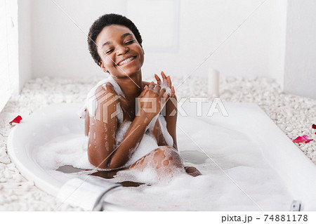 Woman with closed eyes of pleasure taking bath with foam and petals at home Woman with closed eyes of pleasure taking bath with foam and petals at home 74881178
