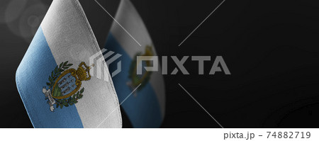Small national flags of the San Marino on a dark background 74882719