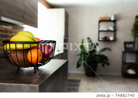 Fruits in fruit bowl on bar counter in stylish loft kitchen. Blurred background Fruits in fruit bowl on bar counter in stylish loft kitchen. Blurred background 74882740