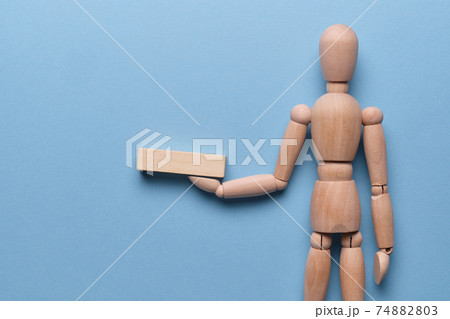 Wooden block holds a mannequin on a blue background. 74882803